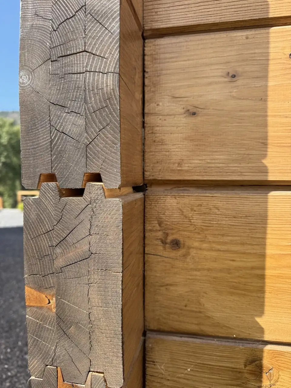 Extremos de madera con grietas junto a las caras laterales de una pared iluminada por el sol
